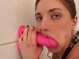 Nubile bi-atch is deep-throating a massive rosy romp toy that's stuck to a wall